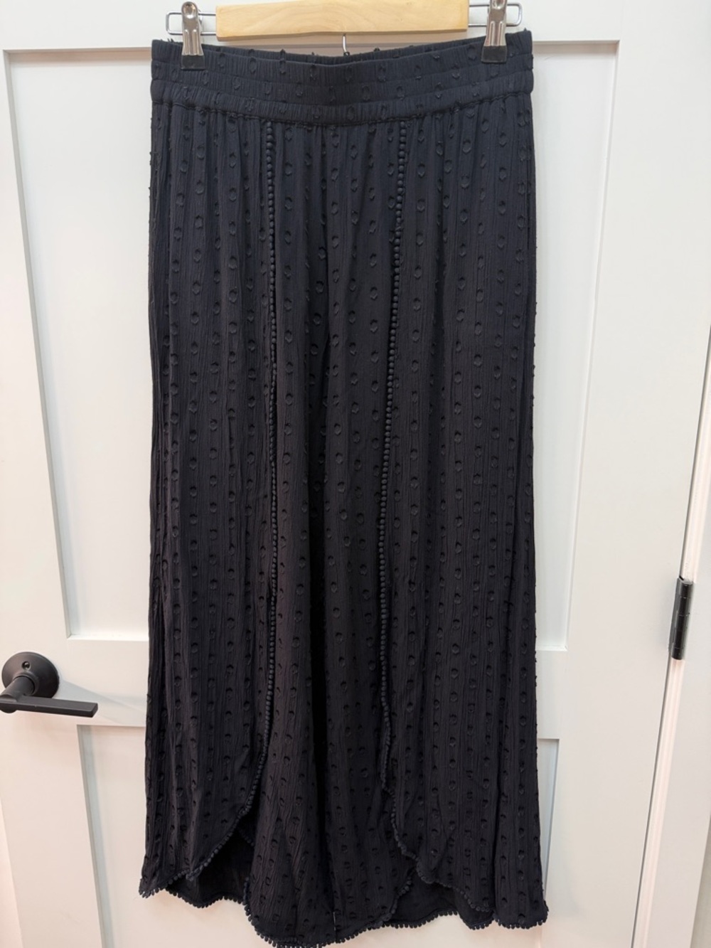 Black pull on palazzo pants with front left leg slits and side pockets.